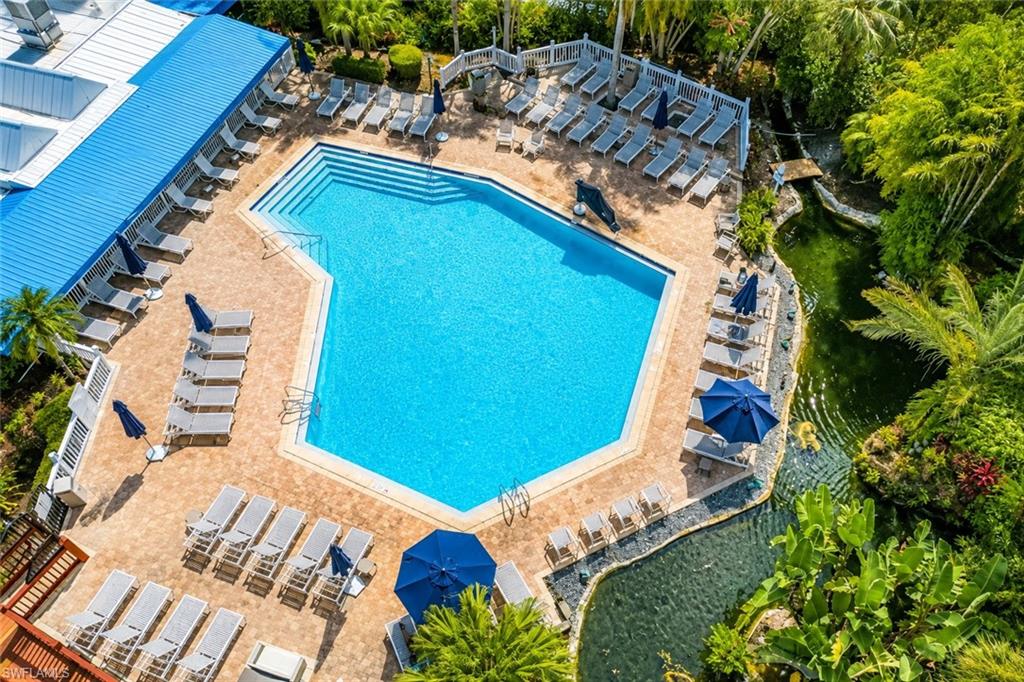 Resort-style pool area featuring a large, geometric swimming pool with integrated steps, surrounded by extensive paver decking