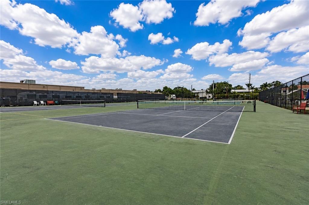 Tennis court facility featuring multiple courts with dark playing surfaces and green surrounds