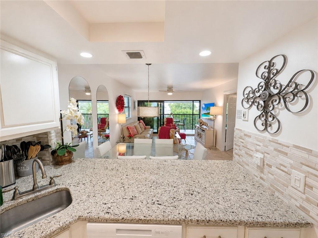 Kitchen featuring granite countertops, a stainless steel sink with a gooseneck faucet, white cabinetry, and a subway tile backsplash