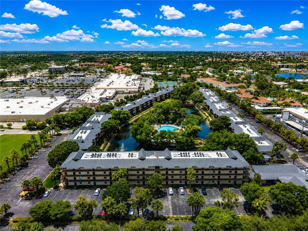 Aerial perspective showcasing a multi-story residential complex with a central pond and swimming pool