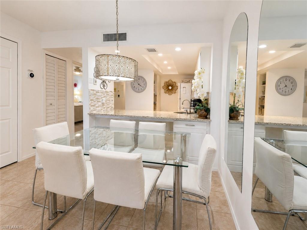 Open-concept dining area featuring tile flooring, a decorative pendant light fixture, and a pass-through counter with a stone-finish surface