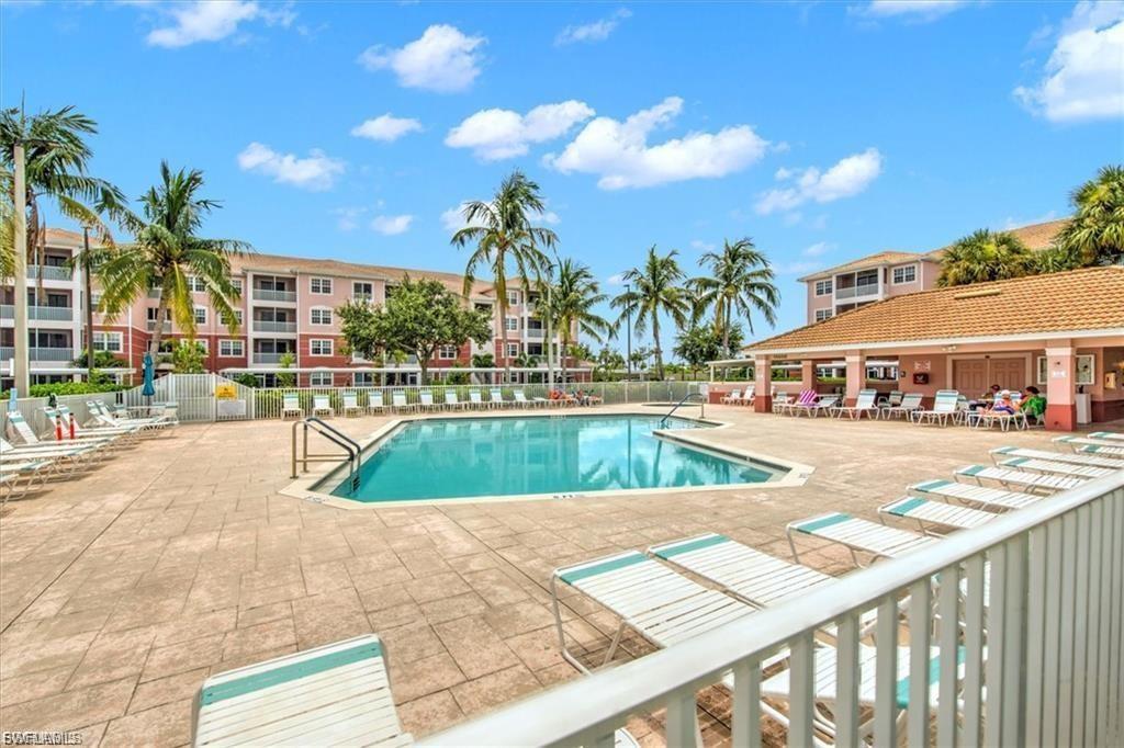 Community swimming pool featuring an integrated spa, surrounding paver deck, and adjacent pool house