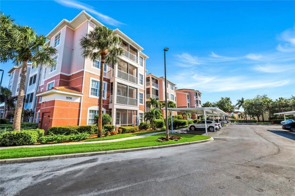 Multi-story residential building featuring screened balconies, a tile roof accent, and lush landscaping
