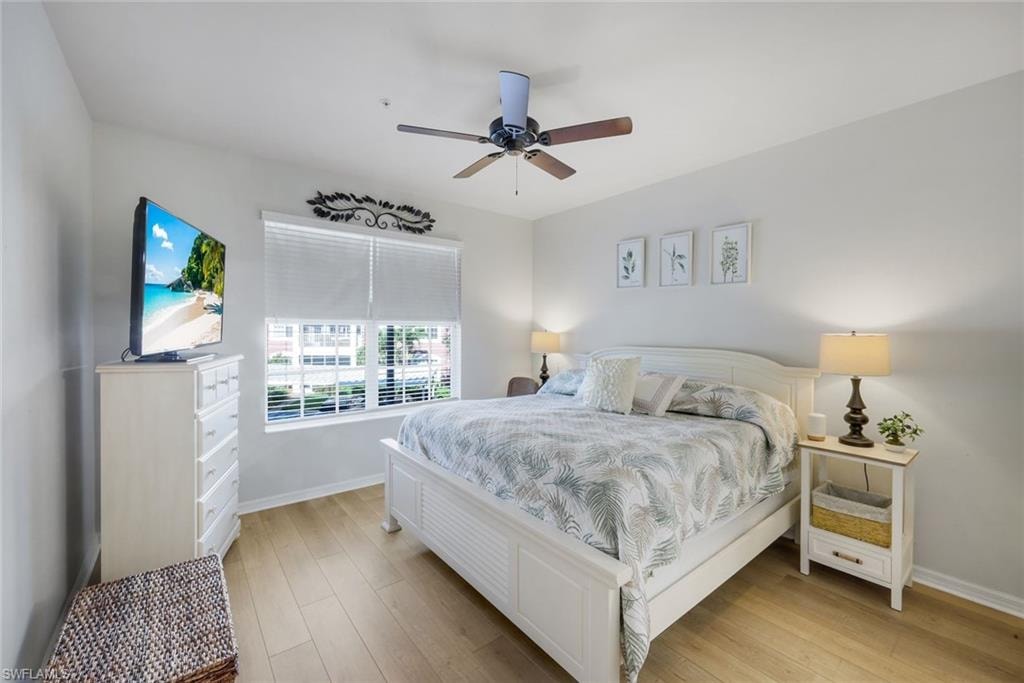 Light-toned wood-finish flooring provides a bright base for this room featuring a window with white blinds, a ceiling fan with integrated lighting, and neutral wall tones
