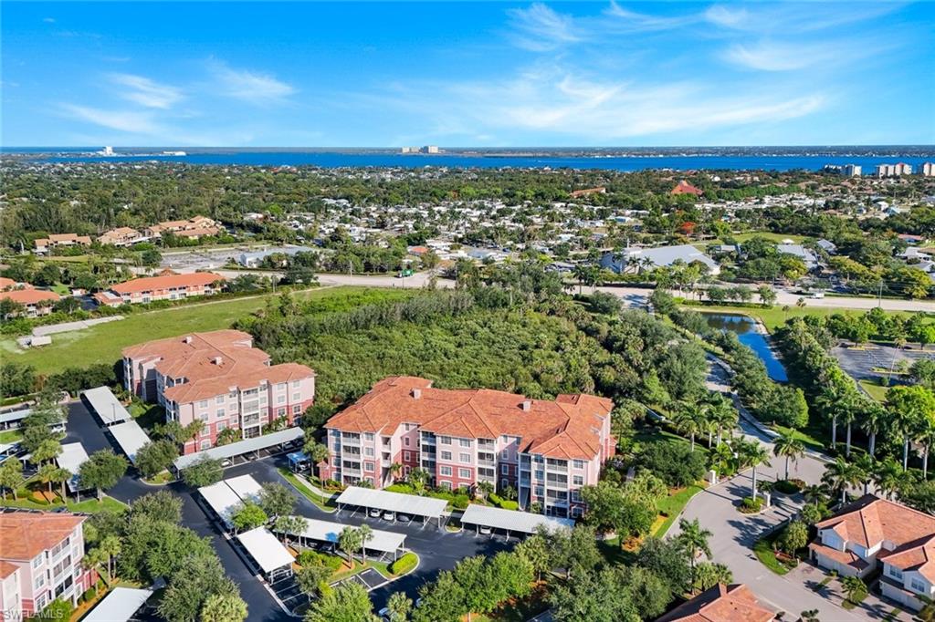 Aerial perspective showcasing multiple residential buildings with terracotta-style roofs, surrounded by extensive green landscaping and mature trees