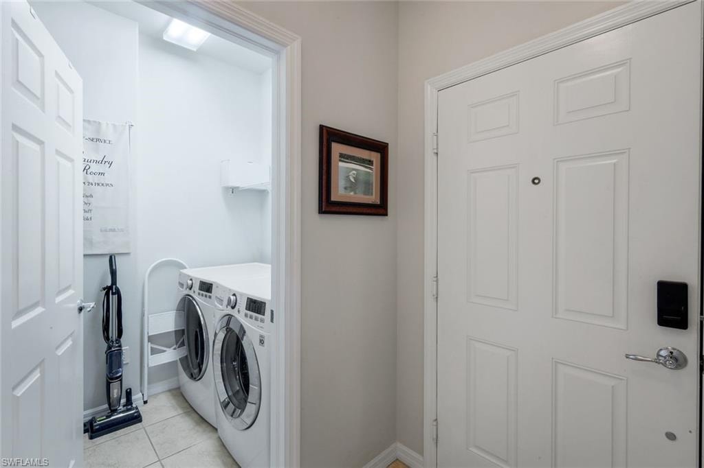 Dedicated laundry area with tiled flooring, featuring a front-loading washer and dryer