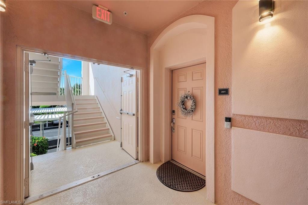 Building entryway featuring a panel door, stucco exterior, and a contemporary wall-mounted light fixture