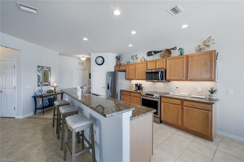 Kitchen featuring light wood cabinetry, stainless steel appliances, a tile backsplash, and recessed lighting