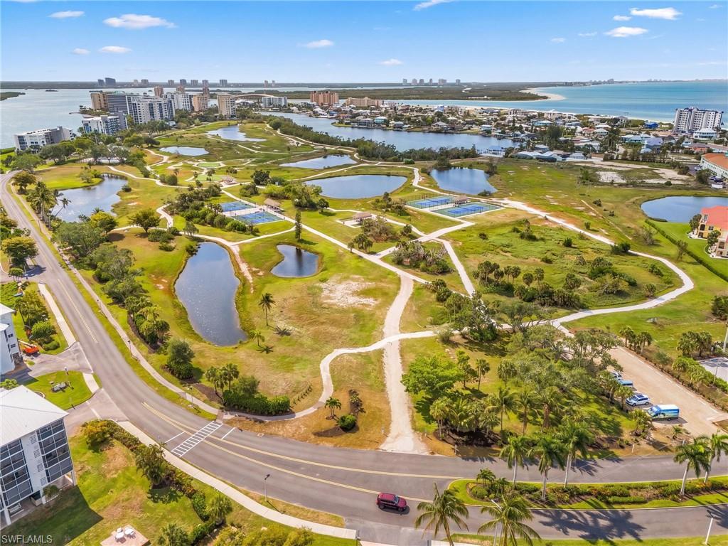 Expansive green space featuring multiple ponds, paved pathways, and tennis courts