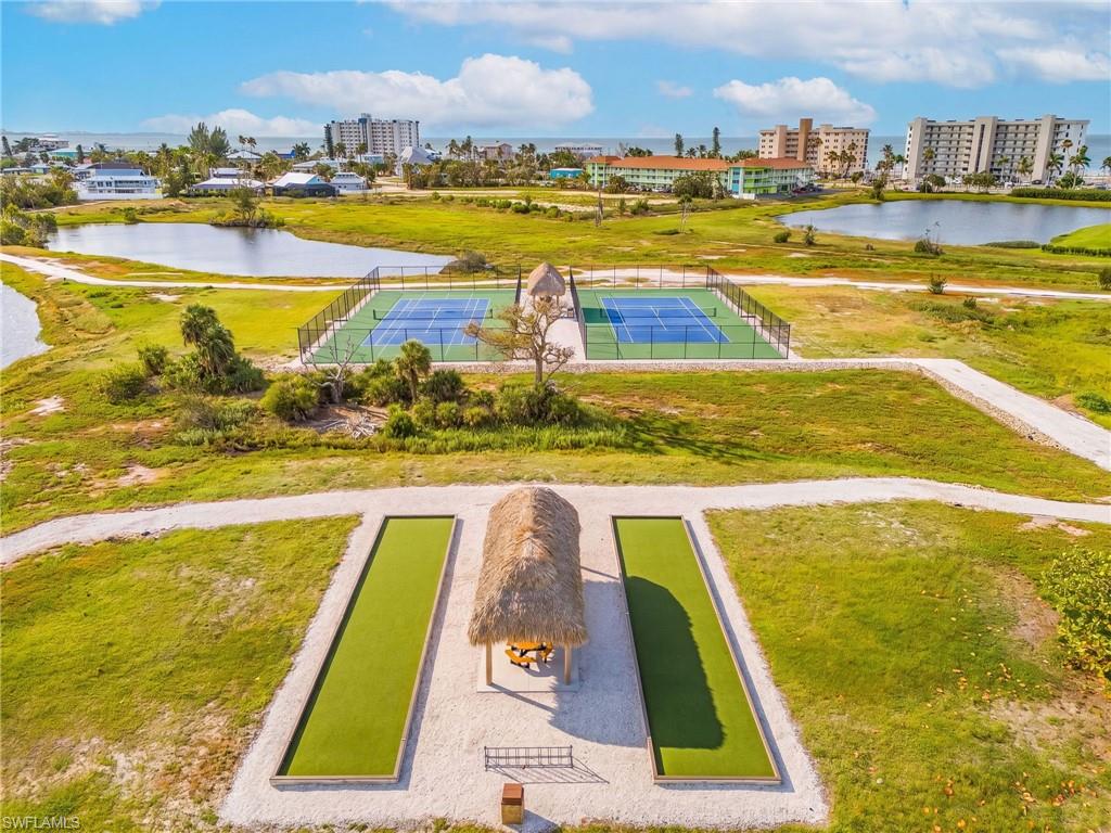 Outdoor amenities featuring two tennis courts, two bocce ball courts with an integrated tiki hut, and surrounding natural landscapes with water features