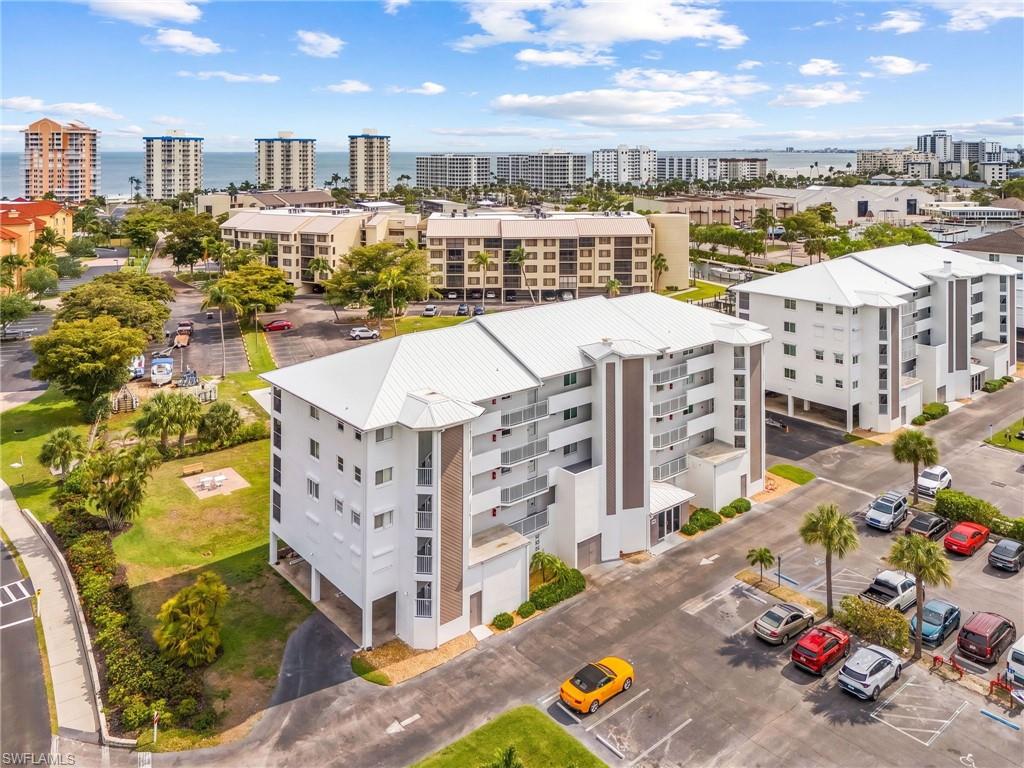 Multi-story condominium building featuring a white exterior and metal roof