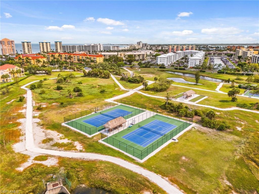 Two tennis courts with blue playing surfaces and green surrounds, complete with a central thatched-roof structure