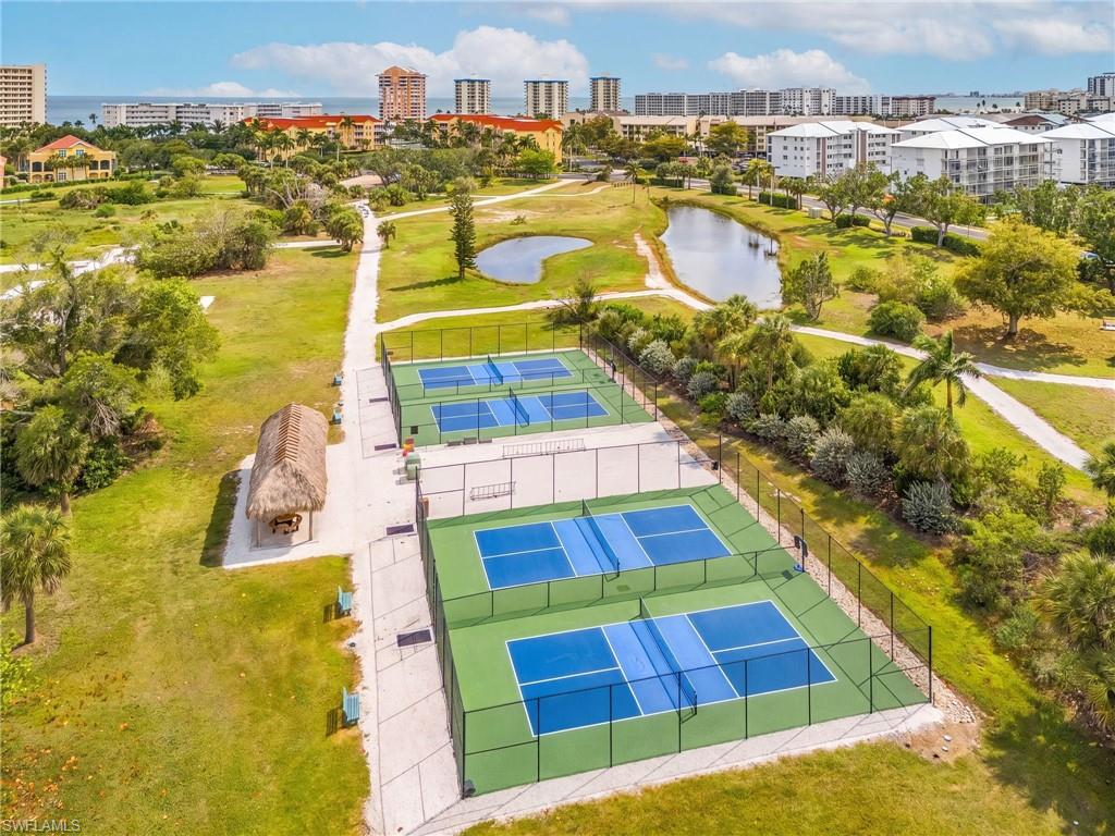 Four fenced pickleball courts with blue playing surfaces