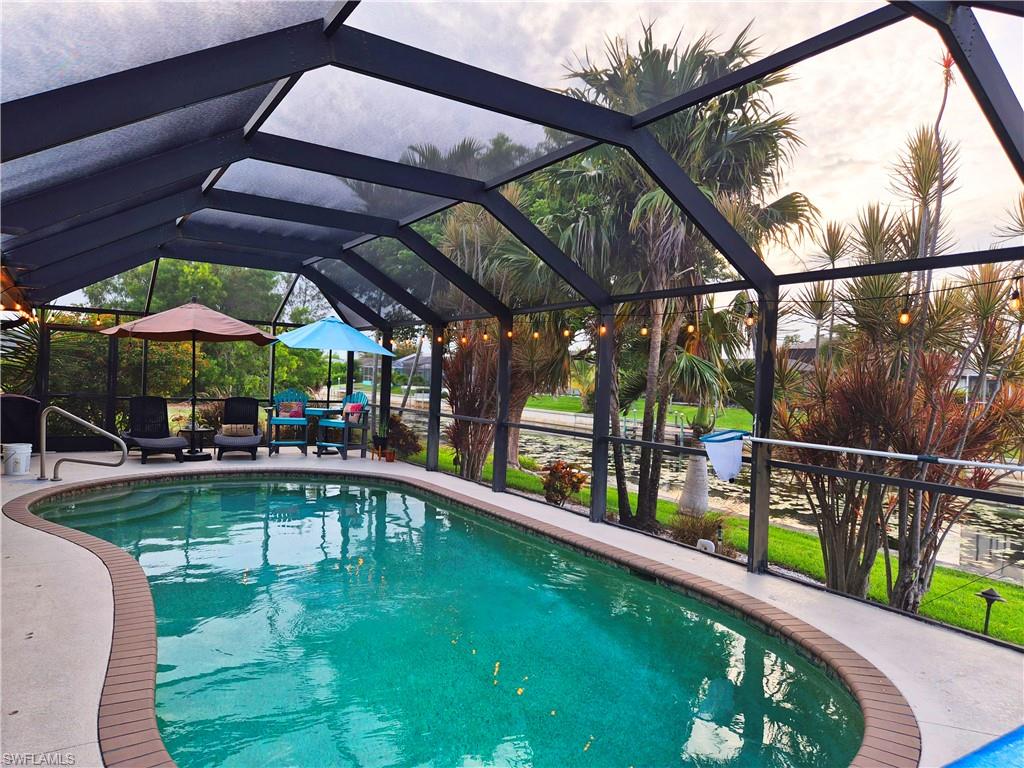 Screened outdoor swimming pool with a curved design, surrounded by a concrete deck and a brick-finish coping