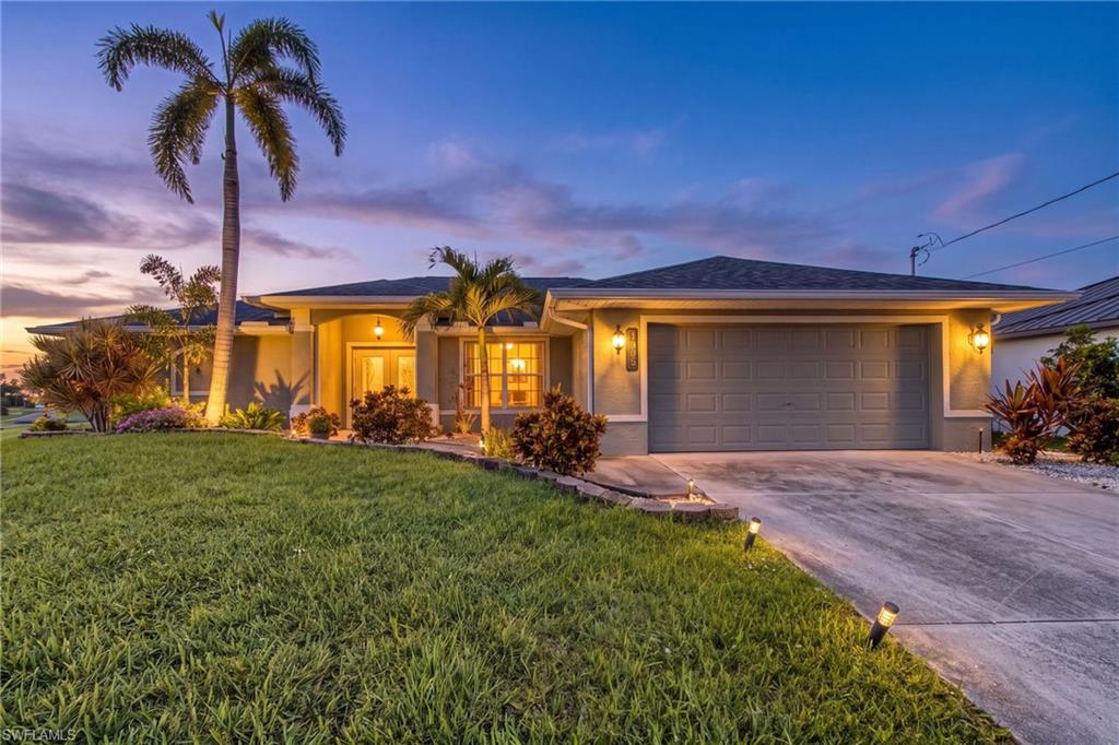 Single-story residence featuring a two-car garage, mature palm trees, and established landscaping