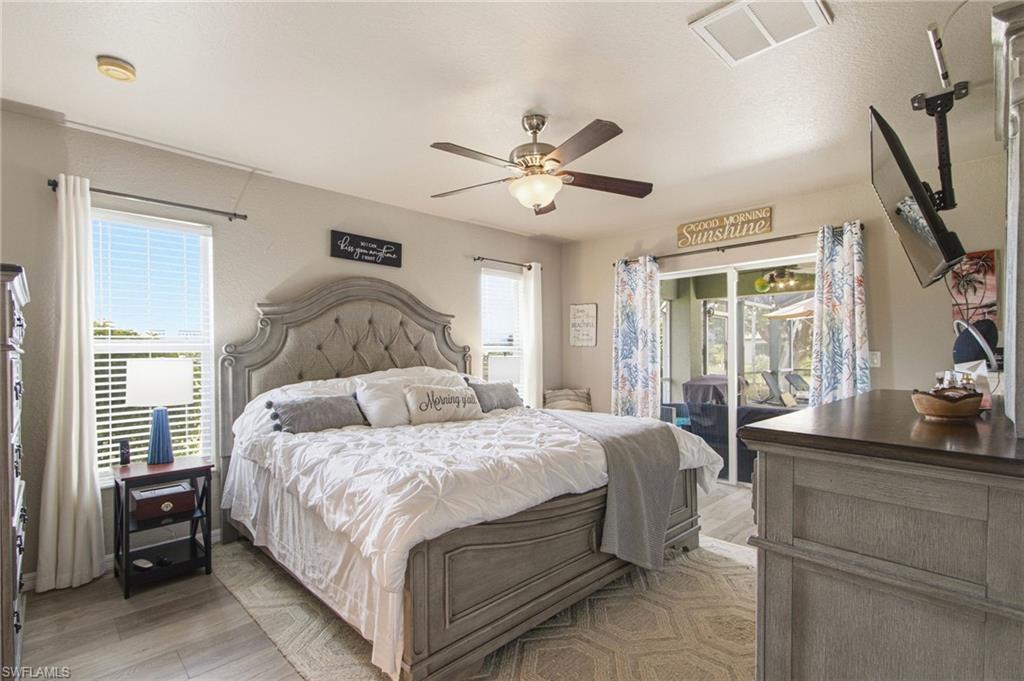 Spacious room featuring wood-finish flooring, a ceiling fan with integrated lighting, and multiple windows with horizontal blinds