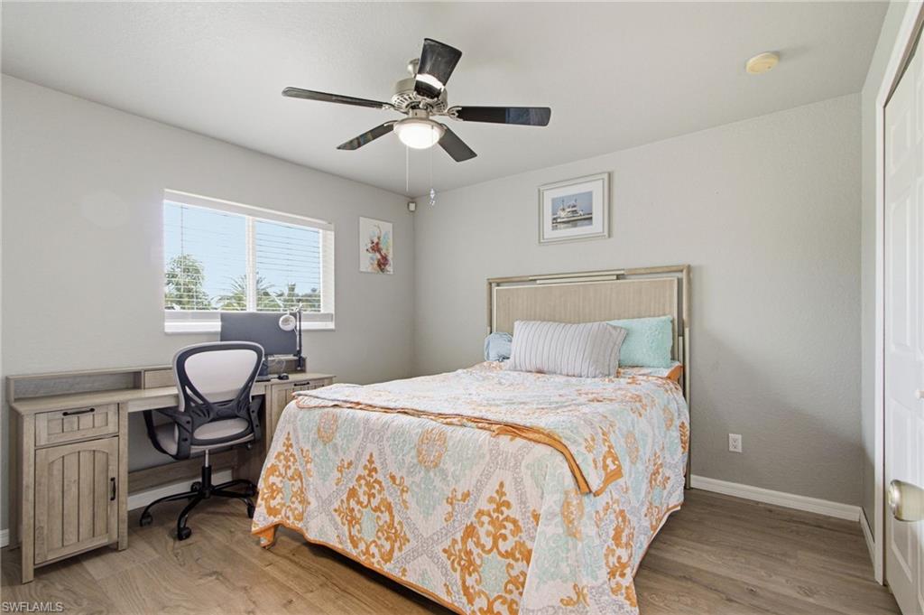 Room featuring wood-finish flooring, a ceiling fan with integrated lighting, and light gray painted walls
