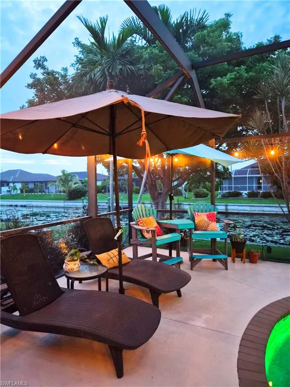 Screened patio with concrete flooring, featuring two chaise lounges and a circular built-in spa