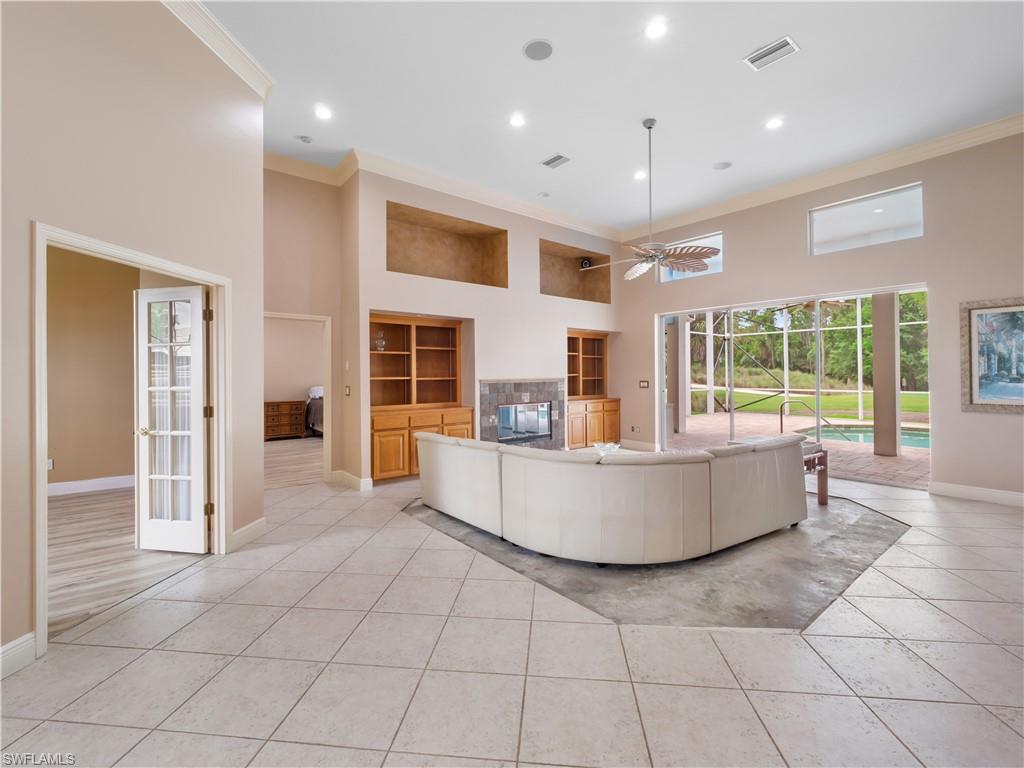 Spacious living area featuring soaring ceilings, a wood-burning fireplace, and expansive views of the outdoor living spaces, ready for your personal design vision.
