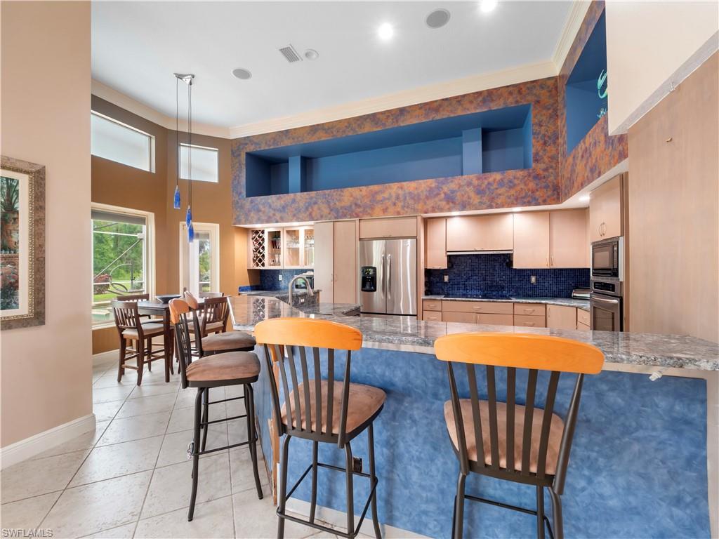 Spacious kitchen and dining area featuring soaring ceilings, abundant natural light, an oversized island, and an open-concept layout ideal for gathering and entertaining.