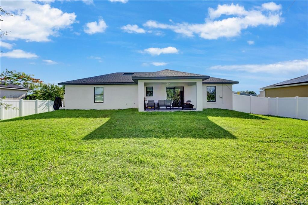 Expansive green lawn with a white privacy fence
