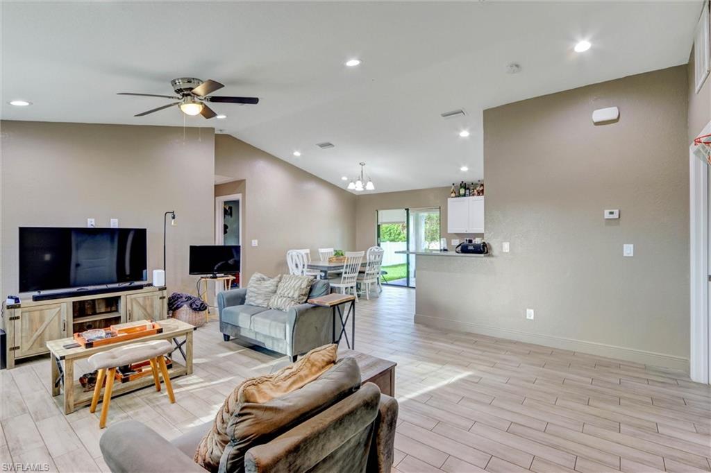 Open-concept living area featuring wood-finish flooring, recessed lighting, and a vaulted ceiling