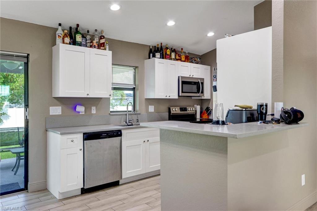 Modern kitchen featuring white shaker cabinetry, stainless steel dishwasher, and a built-in microwave