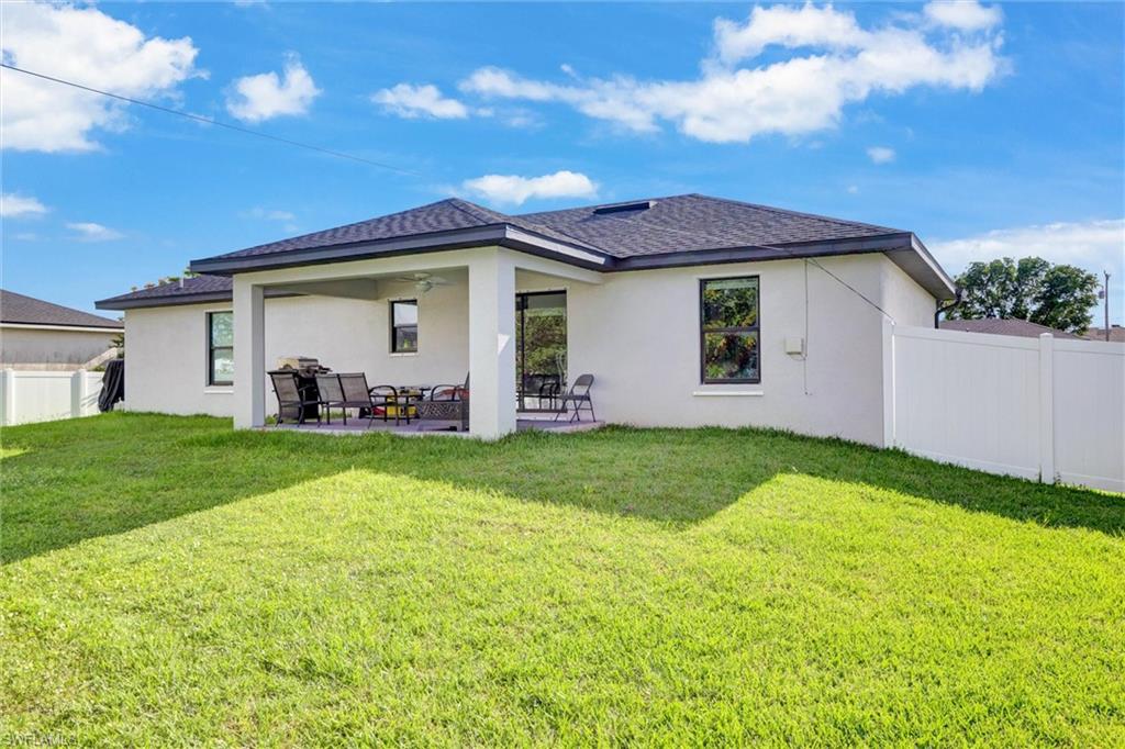 Expansive green lawn bordering a covered patio area with a ceiling fan
