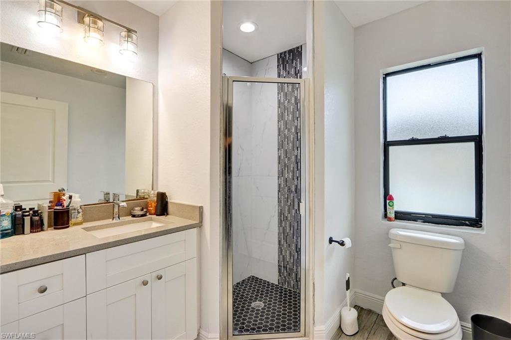 Shower with glass enclosure, white rectangular vanity with integrated sink, and coordinating countertop