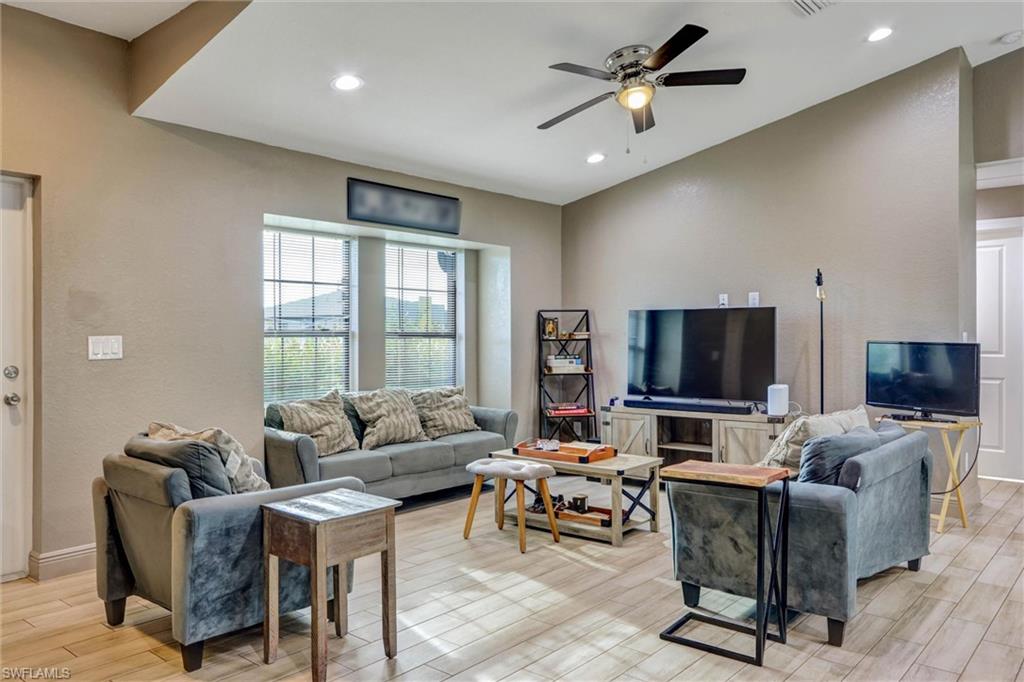 Spacious living area featuring wood-finish flooring, recessed lighting, and a ceiling fan with integrated light