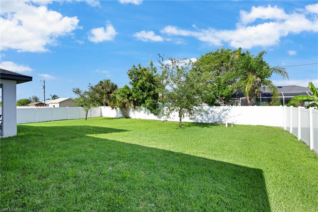 Spacious backyard featuring a lush lawn, privacy fencing, and mature trees