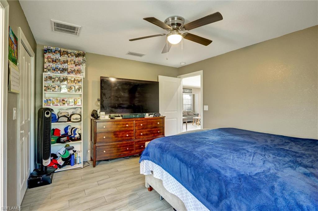 Spacious room featuring wood-finish flooring, a ceiling fan with integrated lighting, and a white interior door