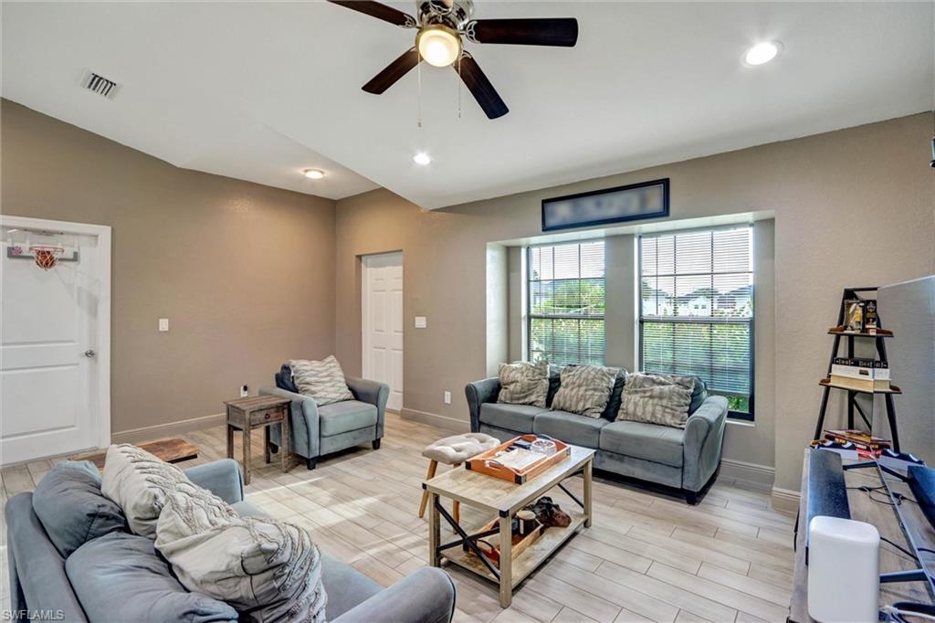 Spacious living area featuring wood-look tile flooring, a vaulted ceiling, and recessed lighting