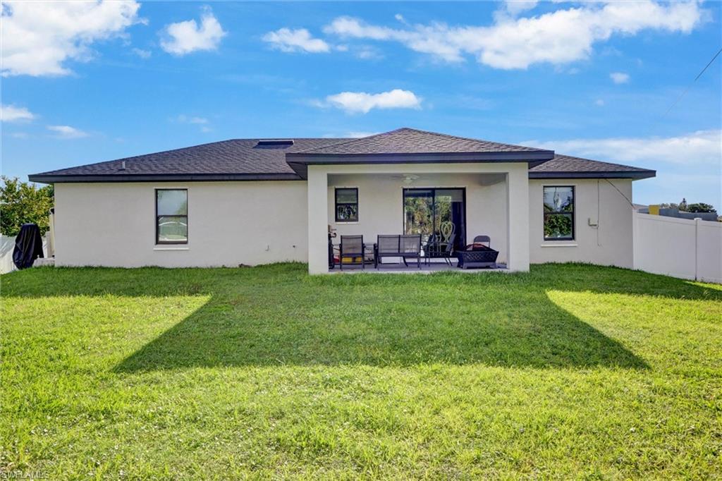 Expansive backyard featuring a manicured lawn, covered patio, and privacy fencing