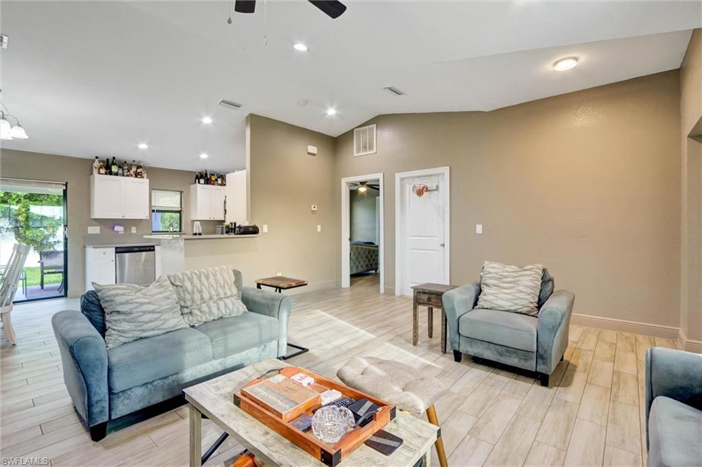 Open-concept living area with wood-finish flooring, vaulted ceilings, recessed lighting, and a ceiling fan