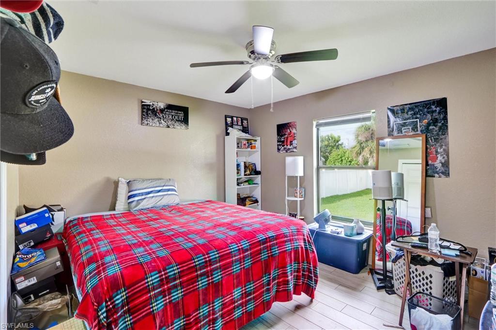 Room featuring textured walls, a ceiling fan with integrated lighting, and wood-finish flooring