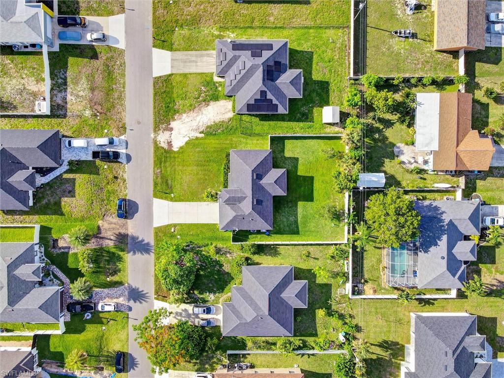 Residential properties featuring concrete driveways, mature landscaping, and fenced backyards