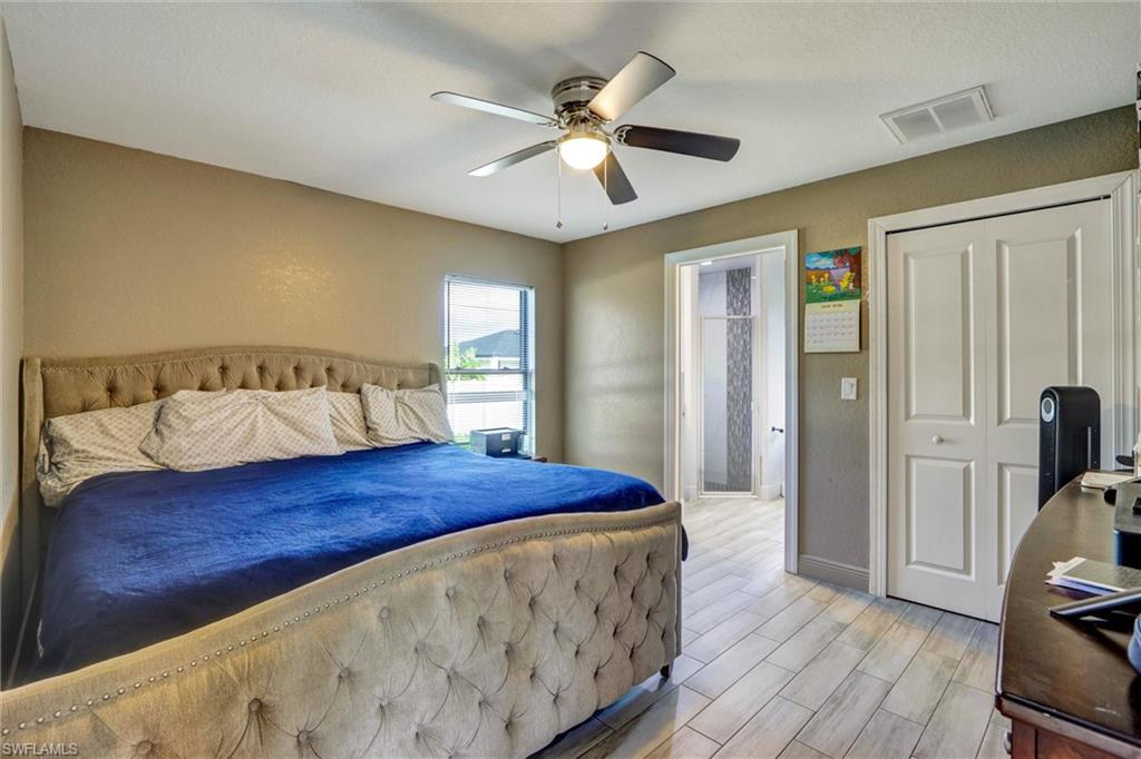 Bedroom featuring neutral wall paint, a ceiling fan with integrated lighting, and wood-look plank flooring