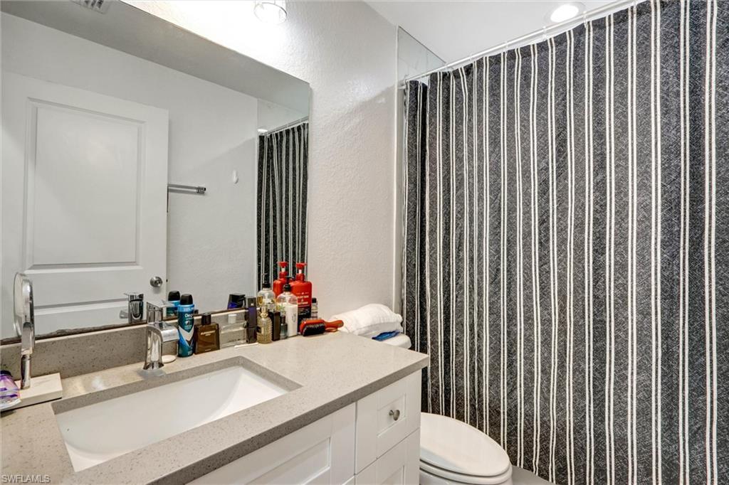 Bathroom vanity featuring a light-toned countertop, undermount sink, and polished chrome faucet