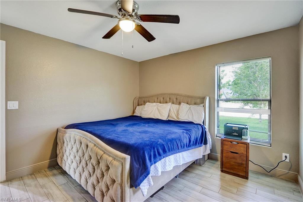 Neutral-toned walls and wood-finish flooring define this room, featuring a ceiling fan with integrated lighting