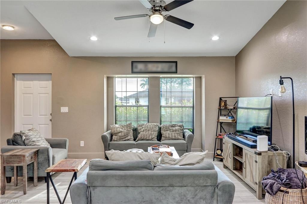 Spacious living area featuring a tray ceiling with recessed lighting and a ceiling fan