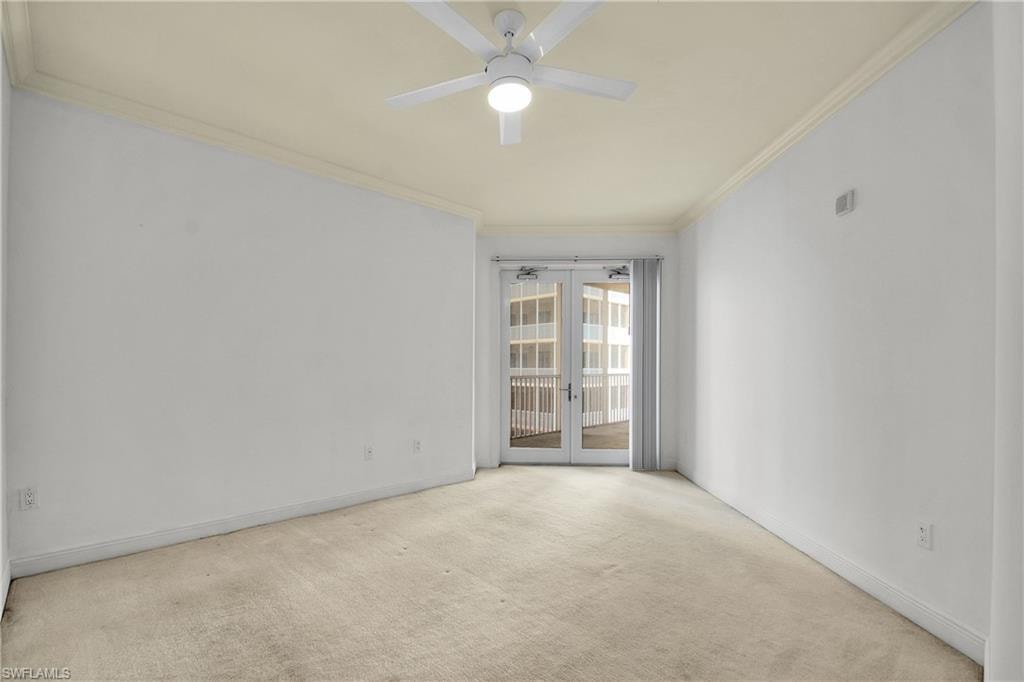 Carpeted empty room featuring ornamental molding, a ceiling fan, and french doors