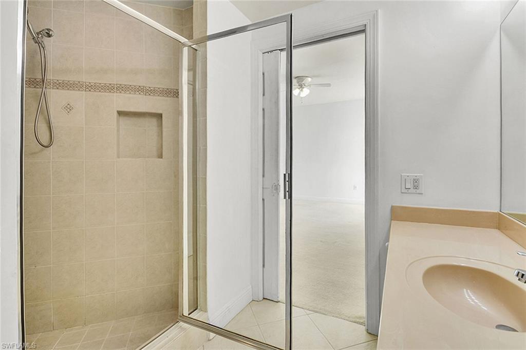 Bathroom with light tile patterned flooring, vanity, a shower stall, and light carpet