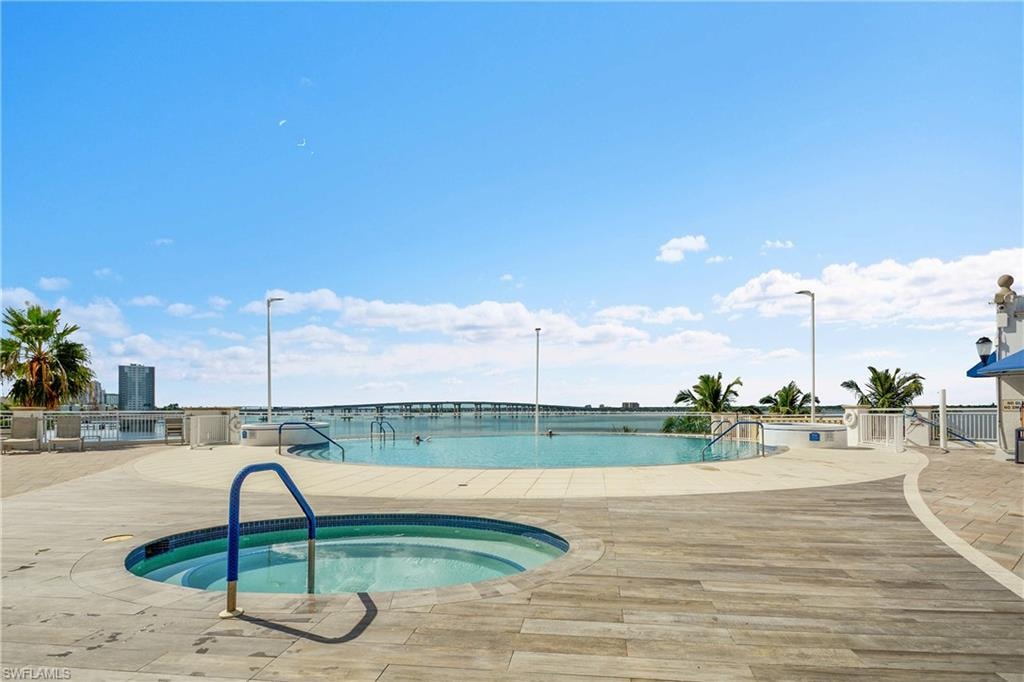 Community pool with a hot tub, a patio area, and a water view