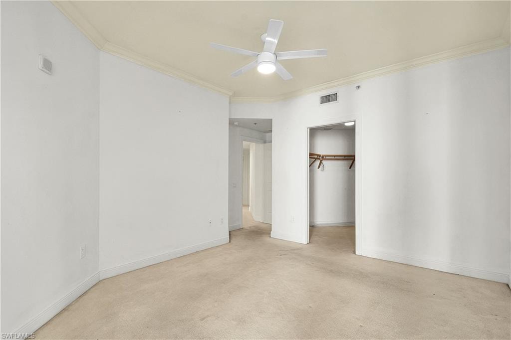 Unfurnished bedroom featuring a closet, crown molding, light colored carpet, and ceiling fan