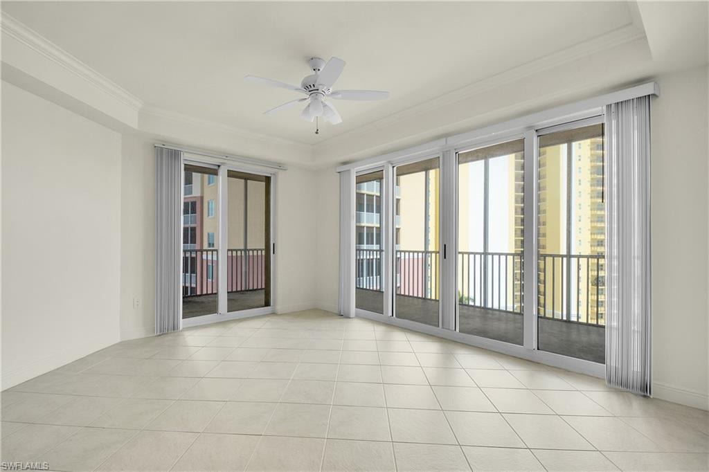 Spare room featuring crown molding, light tile patterned flooring, ceiling fan, and a raised ceiling