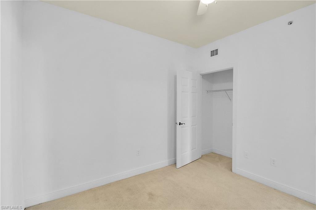 Unfurnished bedroom with light carpet, a closet, and a ceiling fan