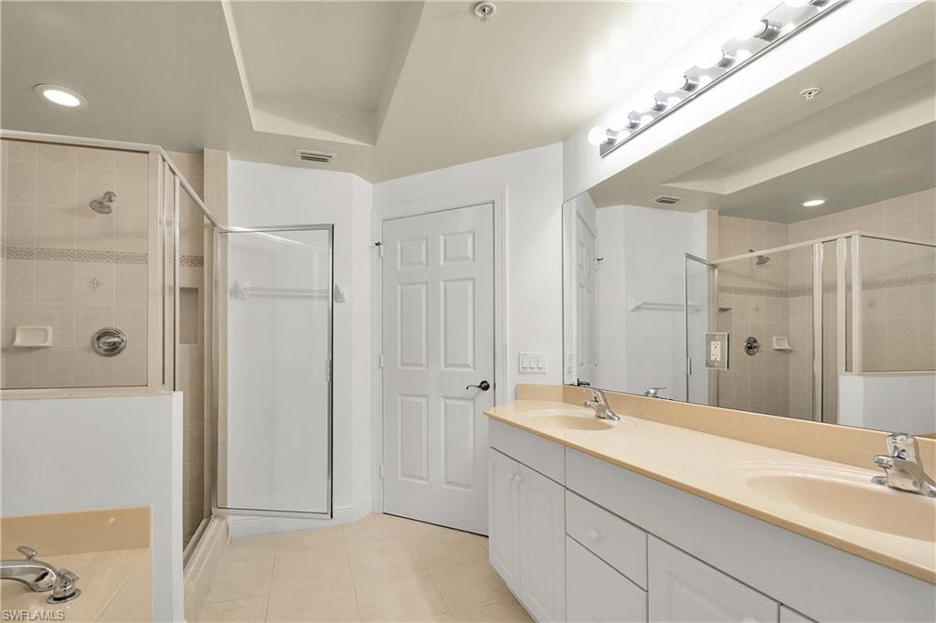 Full bathroom featuring double vanity, recessed lighting, light tile patterned floors, a stall shower, and a garden tub