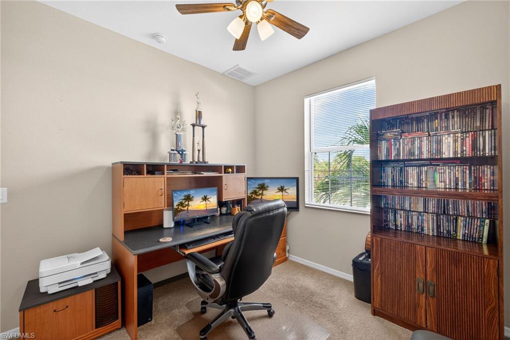 Carpeted room with a ceiling fan, a window with blinds, and a built-in desk unit with integrated storage