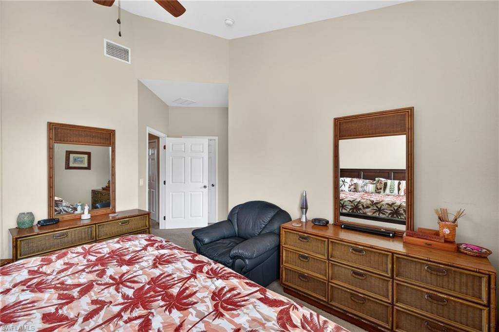 Spacious room featuring vaulted ceilings, neutral wall tones, and a ceiling fan